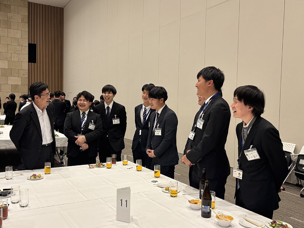 研修最終日の決起会における松田社長(写真左)との新入社員の様子