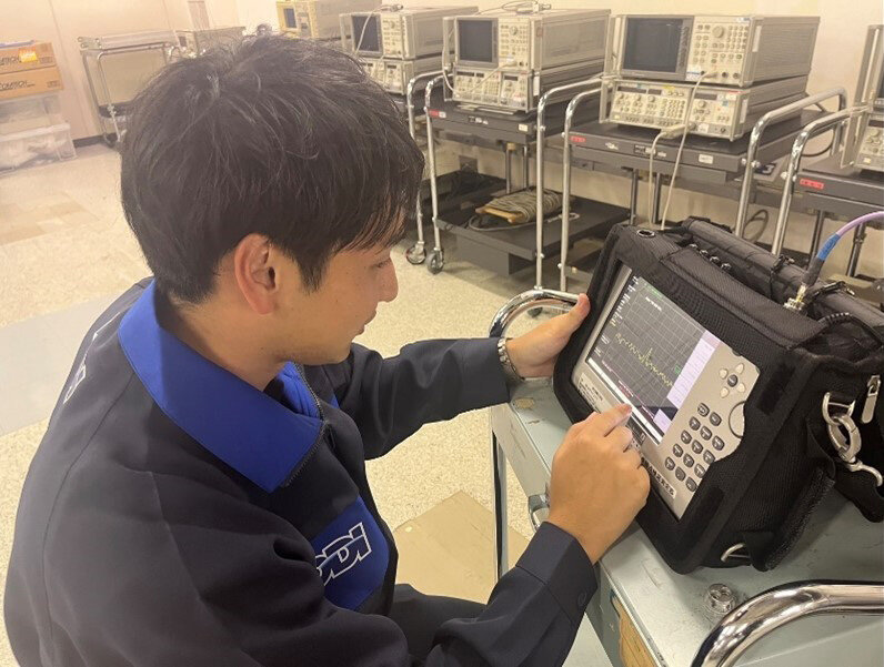 衛星通信設備の受信スペクトルを確認する松原さん