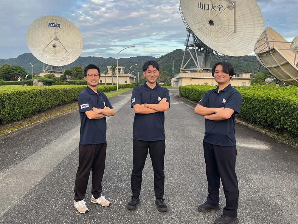 松原さんと衛星通信所社員の写真